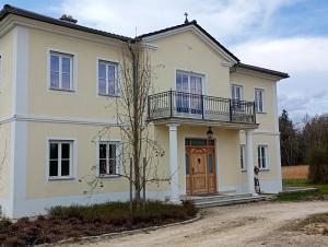 une grande maison blanche avec une porte en bois dans l'établissement Cottage Living, à Leiblfing