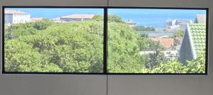 two windows in a room with a view of trees at Salt Bungalow Yzerfontein in Yzerfontein