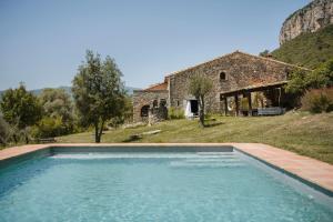 a swimming pool in front of a stone house at La Casa de la Llum in Amer