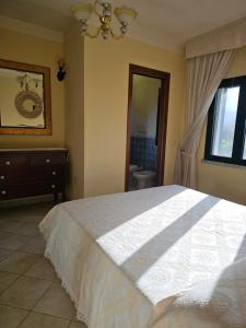 ein Schlafzimmer mit einem weißen Bett und ein Badezimmer in der Unterkunft Prestigiosa villa La Cinta in San Teodoro