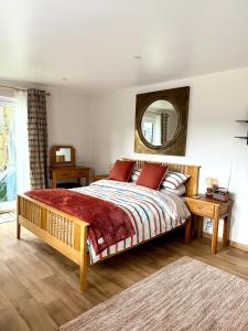 a bedroom with a large bed and a mirror at Acorn Lodge Pentewan in St Austell
