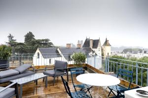 a balcony with chairs and tables and a view of a city at grand gîte terrasse vue Loire et château d'Ancenis in Ancenis