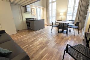 a living room with a table and chairs and a kitchen at Molière ChicSuites in Paris +25 photos
