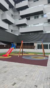 einen Spielplatz vor einem Gebäude mit Schaukeln in der Unterkunft KOTA Zero Rivas Center 500 in Rivas-Vaciamadrid