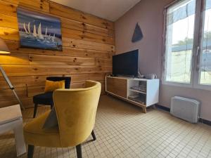 a living room with a wooden wall with a tv and a chair at Maisons de vacances 6 pers proche plan d'eau in L'Aiguillon-la-Presqu'île