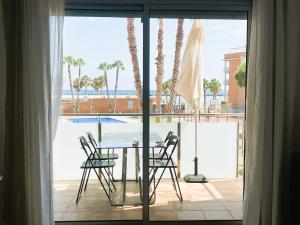 a table and chairs on a balcony with a view of a pool at Rose - Primera línea de mar, piscina, wifi, parquing in Cubelles