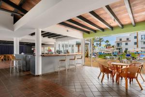 a patio with a bar and tables and chairs at Vibra Blanc Cottage Apartmentos - 3SUP in Sa Caleta
