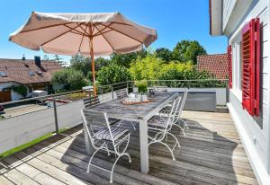 a table and chairs on a deck with an umbrella at Villa Kunterbunt in Lindau