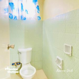 a bathroom with a toilet in a green tiled room at 2-BR Narra Unit by The Pineview Chateau in Baguio +29 photos