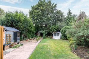 een achtertuin met een tuin en een kas bij Lennox Road Small Rooms Inn in Bletchley +1 foto