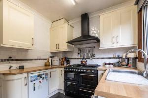 een keuken met witte kasten en een zwarte oven bij Lennox Road Small Rooms Inn in Bletchley