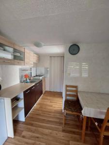 a kitchen with a table and a dining room with a clock on the wall at Domek letniskowy ,,Jolczyn'' in Nowęcin