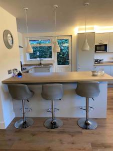 a kitchen with a counter with three bar stools at Holiday Bungalow in Arnside in Arnside +40 photos