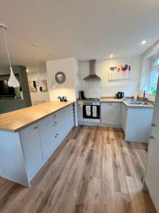 a large kitchen with white cabinets and wooden floors at Holiday Bungalow in Arnside in Arnside