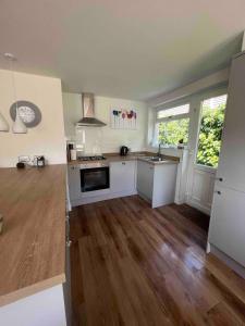 a kitchen with white cabinets and a wooden floor at Holiday Bungalow in Arnside in Arnside
