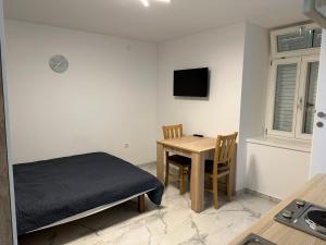 a room with a table and a bed and a table and chair at Mimis Apartments in Novalja