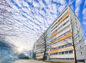 a tall building with a cloudy sky in the background at Geräumige Ferienwohnung mit Parkplatz direkt an der S-Bahn nach München in Unterschleißheim