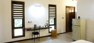 eine Küche mit einem Kühlschrank sowie einem Tisch und Stühlen in der Unterkunft Mangi's Tranquil Bangalows in Pinnawala