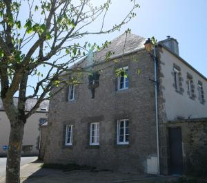 an old brick building with white windows and a tree at Les Hortensias in Lanvénec