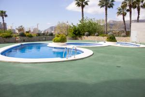 a group of three swimming pools with palm trees at Apartamentos Topacio Unitursa in Calpe