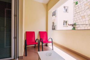 two red chairs on the balcony of a building at Luxur house with seaview teracce in Baška Voda