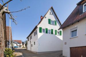 a white house with green windows on a street at Ferienwohnung Sila 3 in Weinstadt