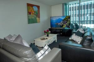 een woonkamer met een bank en een flatscreen-tv bij Coastal Bliss 2 Bedroom Apartment in Gold Coast