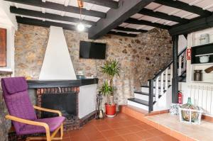 a living room with a fireplace and a purple chair at Cosy House in Isongo in Isongo