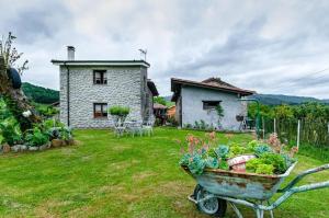 a garden with a wheelbarrow of vegetables in front of a house at Cosy House in Isongo in Isongo +9 photos
