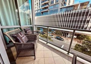 een balkon met een stoel en uitzicht op de stad bij Coastal Bliss 2 Bedroom Apartment in Gold Coast