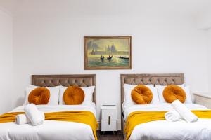 two beds with orange pillows in a room at Mayfair Residences in London