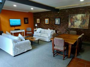 a living room with white furniture and a wooden table at The Clarens Country House in Clarens