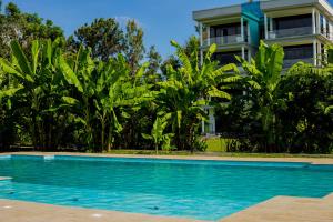 a villa with a swimming pool in front of a house at Shose Farmhouse Chalets & Campsite in Moshi
