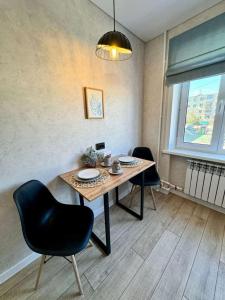 a dining room with a table and chairs and a window at Квартира 4-40 in Balqash