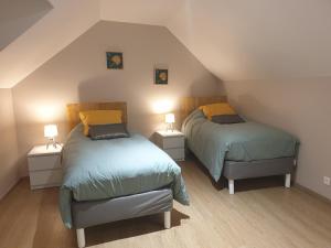 a attic bedroom with two beds and two lamps at Maison de charme avec jardin au bord de l'Eure in Le Vaudreuil
