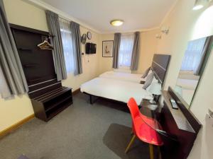 una camera da letto con un letto bianco, una scrivania e una sedia rossa di Epsilon Hotel a Londra