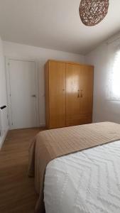 a bedroom with a bed and a wooden cabinet at Apartamento Murales de Talavera in Talavera de la Reina
