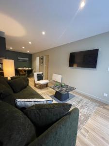 un salon avec un canapé et une télévision sur un mur dans l'établissement COSY TERRASSE 6 pers Ax Thermes Centre Parking, à Ax-les-Thermes