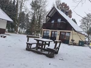 FrielendorfにあるFerienhaus Tindy am Silberseeの雪の中のピクニックテーブルとベンチ