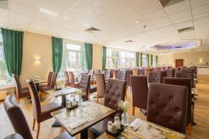 a dining room with tables and chairs and green curtains at Seehotel Brandenburg an der Havel in Brielow