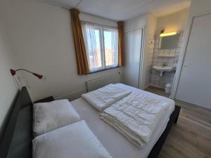 エグモント・アーン・ゼーにあるDe Groten Zesのベッドルーム1室(白いシーツとシンク付きのベッド1台付)