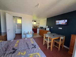 a bedroom with a bed and a table and a kitchen at Le Paradis de Marie in Treignac
