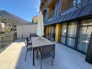 une table et des chaises avec un parasol sur un balcon dans l'établissement COSY TERRASSE 6 pers Ax Thermes Centre Parking, à Ax-les-Thermes