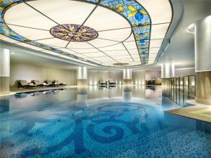 西寧市にあるThe Sebel Xining-Managed By Sofitelのホテルロビーのステンドグラスの天井があるプール