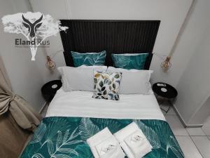 a bed with green and white sheets and pillows at Eland Rus Micro Stay Self Catering in Kathu