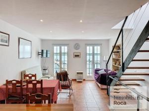 a living room with a table and a staircase at Roca Fornells, Maritim 53 - F275 in Fornells