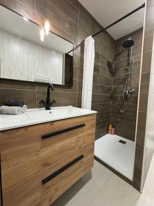 a bathroom with a sink and a shower with a mirror at Appartement 300m de la mer in Valras-Plage