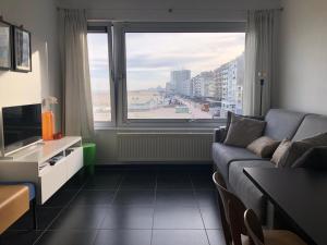 a living room with a couch and a large window at Oostduinkerke Estacade ZEEDIJK in Oostduinkerke