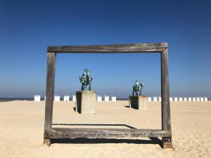 a mirror on the beach with two statues in it at Oostduinkerke Estacade ZEEDIJK in Oostduinkerke