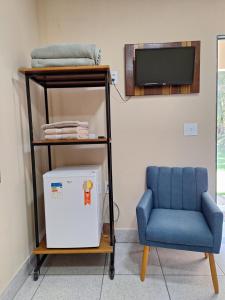 a room with a blue chair and a television at Pousada DuBaldo in Holambra